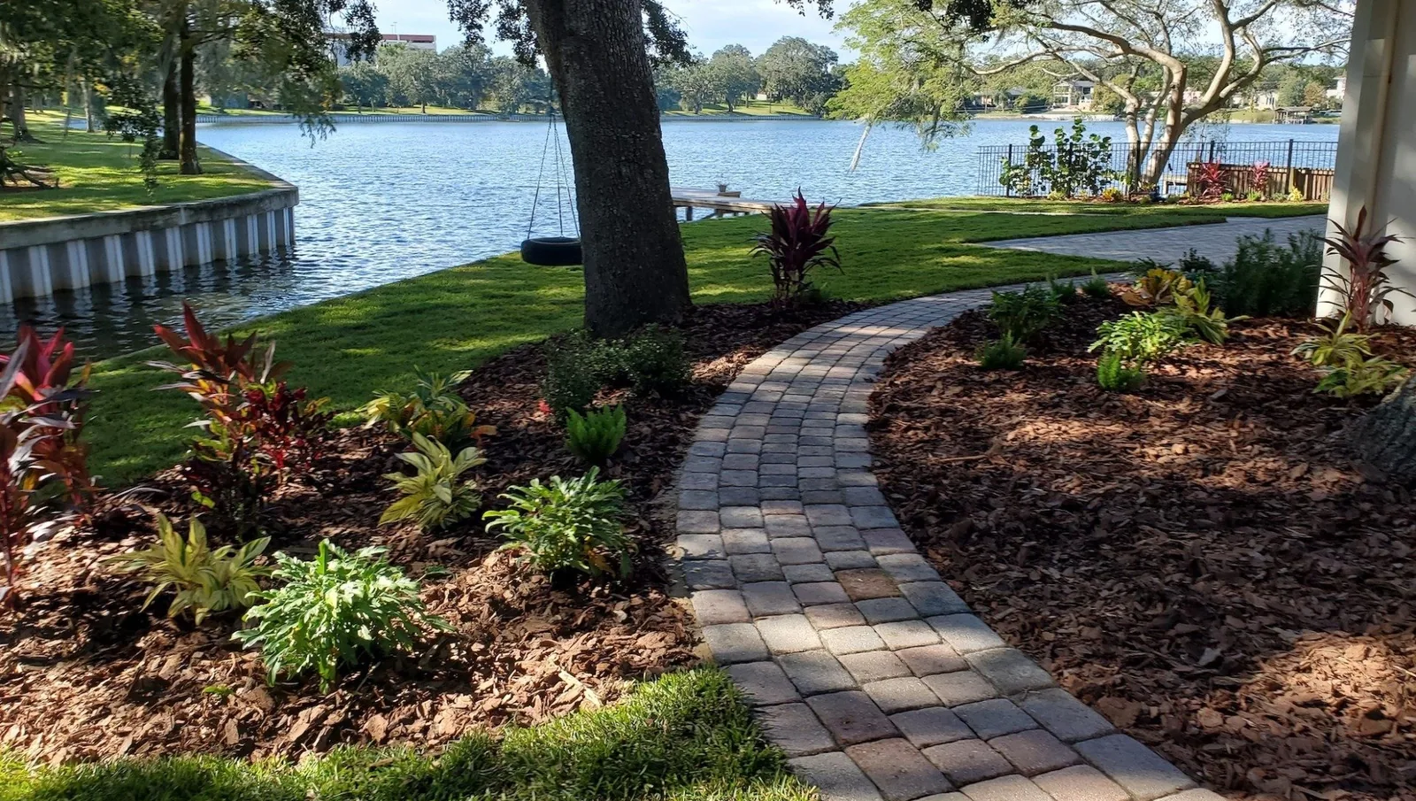 A curved paver walkway through fresh planting beds running down to a Central Florida lakefront