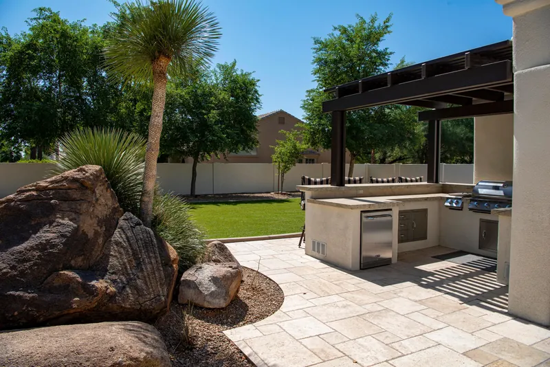 A finished paver patio with outdoor kitchen and mature planting