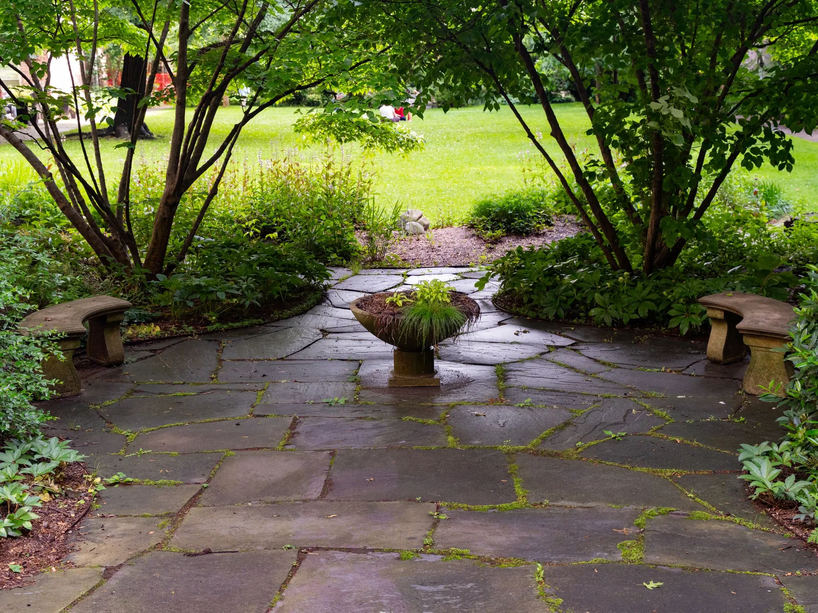 A finished stone patio surrounded by mature planting