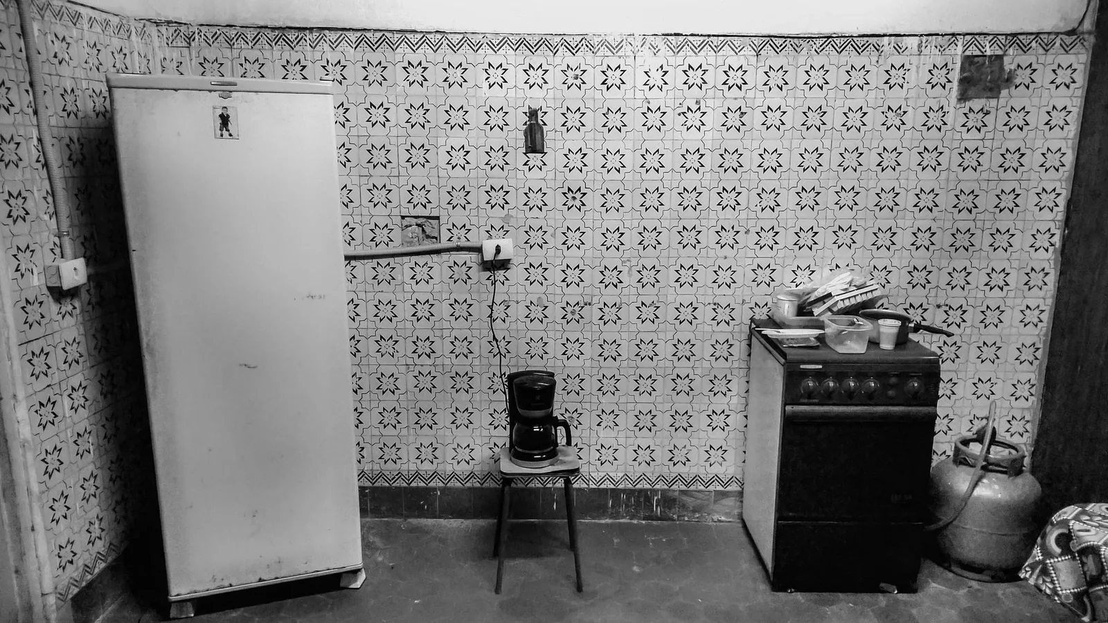 Before: a dated, stripped-back galley kitchen with dark tile and a load-bearing centre wall