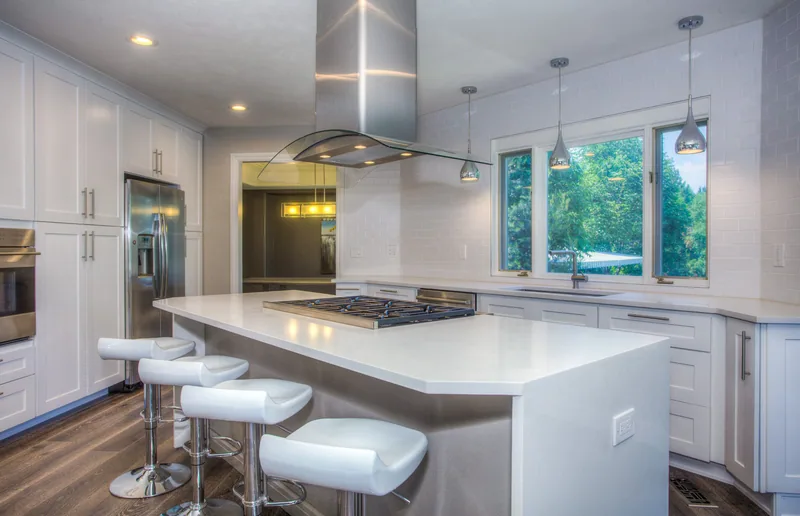 Minimal white kitchen with waterfall stone island and integrated appliances