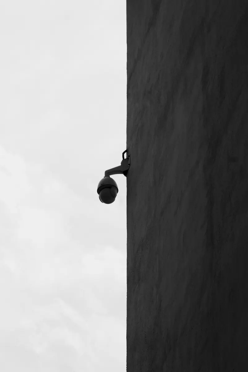 A single security camera mounted high on a dark exterior wall