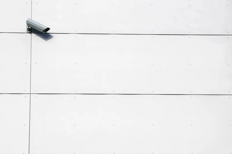 A single discreet camera on a plain rendered wall