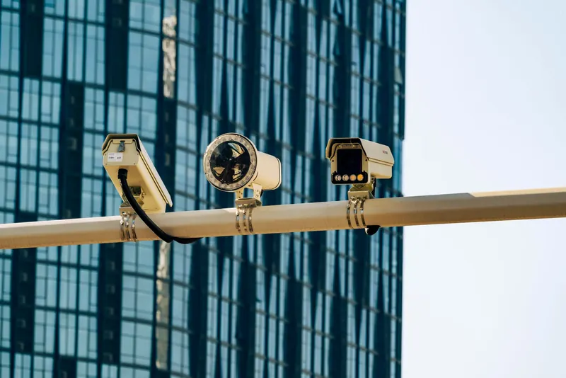 Cameras mounted on a pole against a blue glass tower