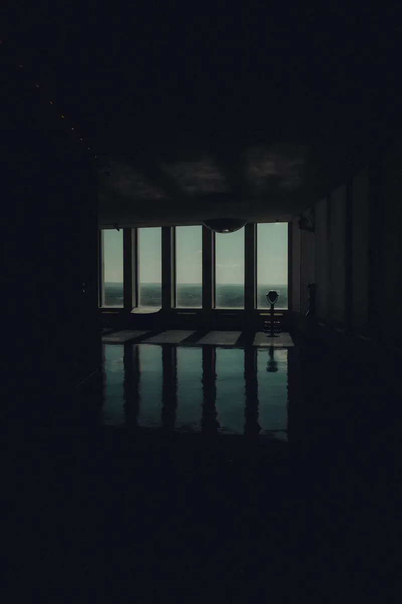 A dark interior looking out through tall windows at night