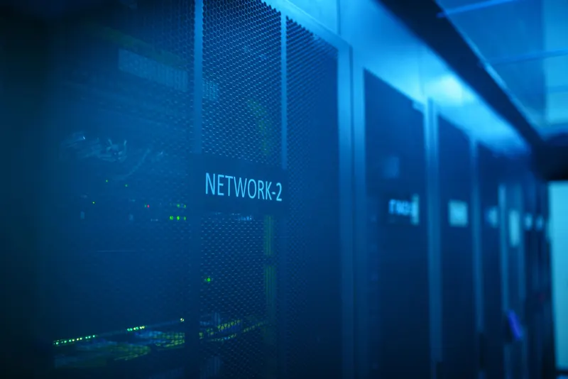A dark equipment aisle lit blue, racks receding into the distance