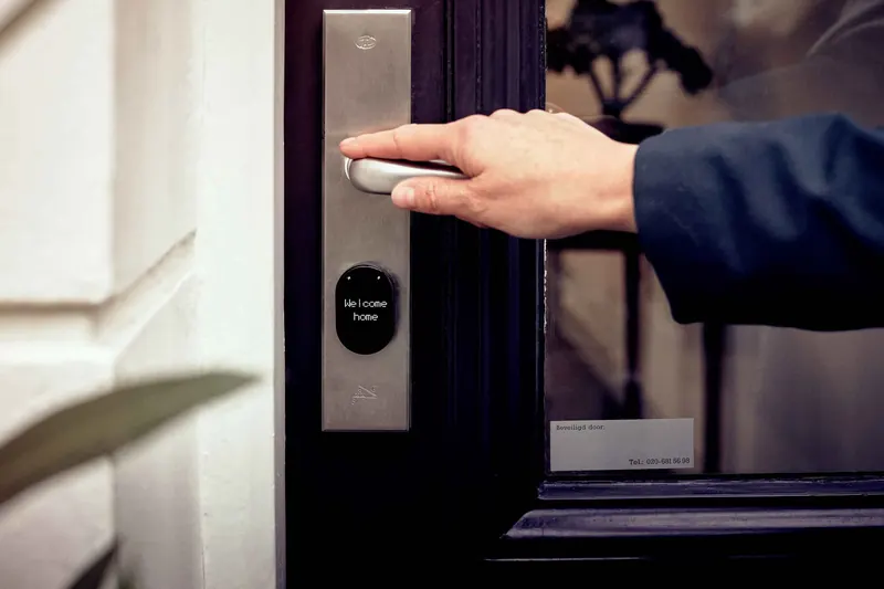 A hand resting on a wall-mounted entry control panel in a dark hallway