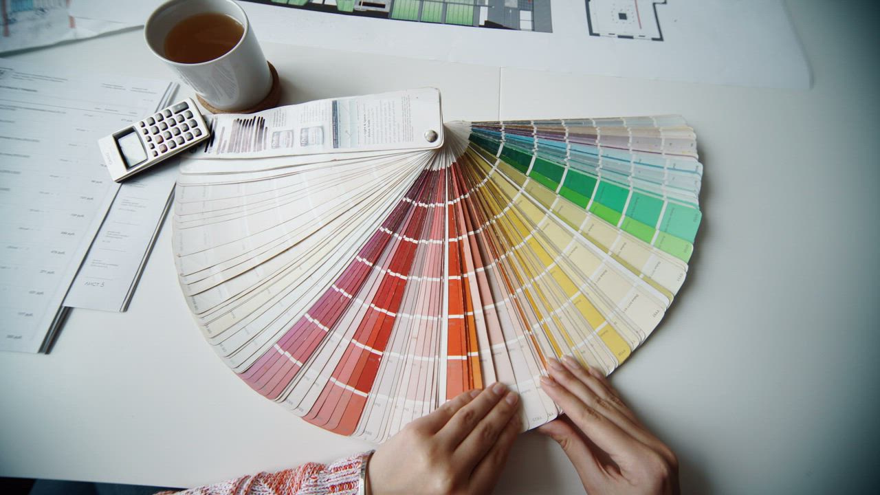 Designer comparing paint and finish swatches against measured kitchen drawings